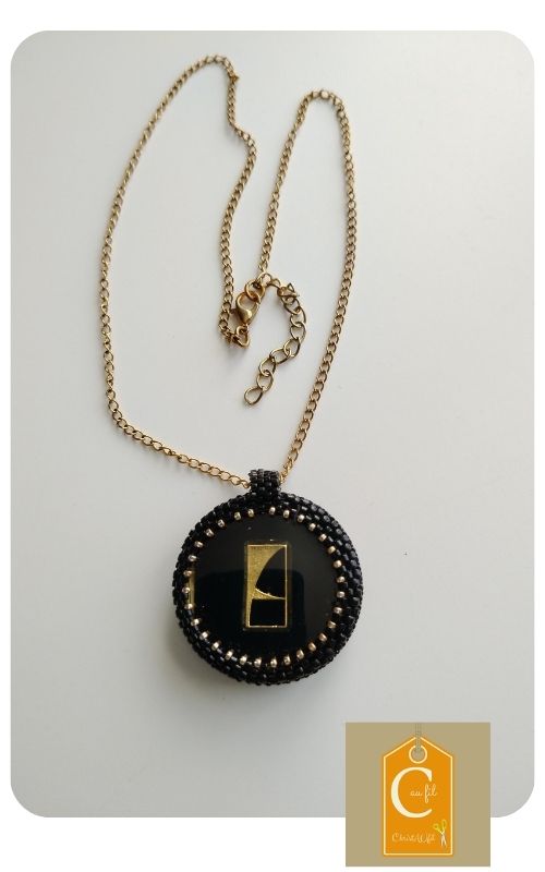 Médaillon rond, bouton noir brillant et motif géométrique or - pendentif chic et moderne sur chaine dorée