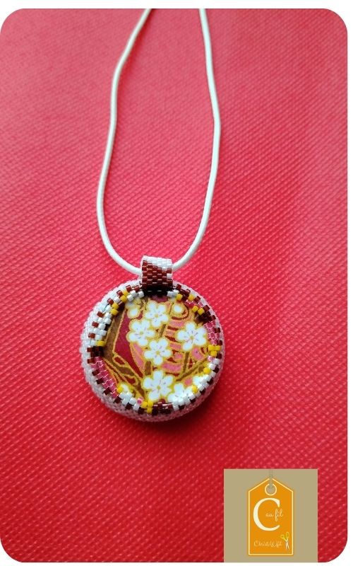 Douceur nacrée d'un bouton vintage et élégance florale d'un papier japonais bordeaux et or.