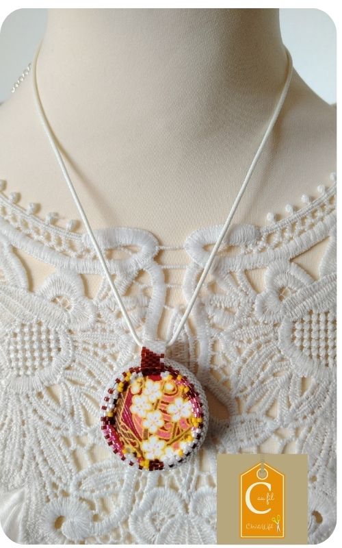 Douceur nacrée d'un bouton vintage et élégance florale d'un papier japonais bordeaux et or.